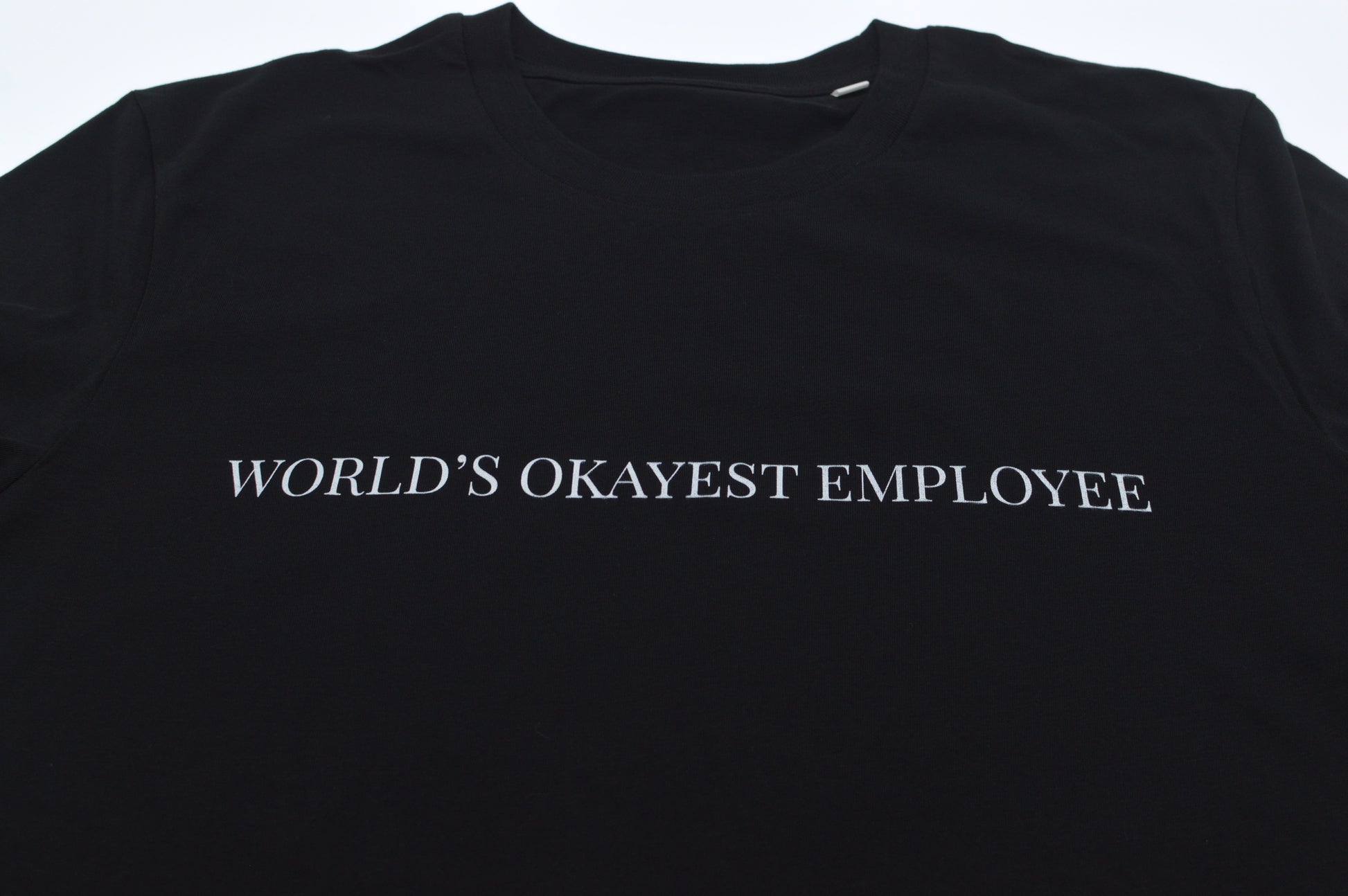 Black t-shirt with 'World's Okayest Employee' text on a white background