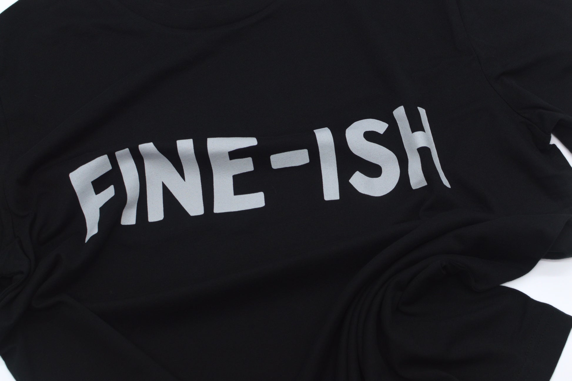 Closeup of Black  shirt with 'FINE-ISH' text on a white background