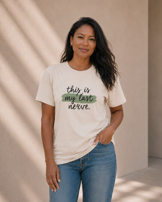 Woman wearing The Bare Minimum Club's vintage white 'This Is My Last Nerve' graphic t-shirt, hand in pocket, standing against a sunlit wall